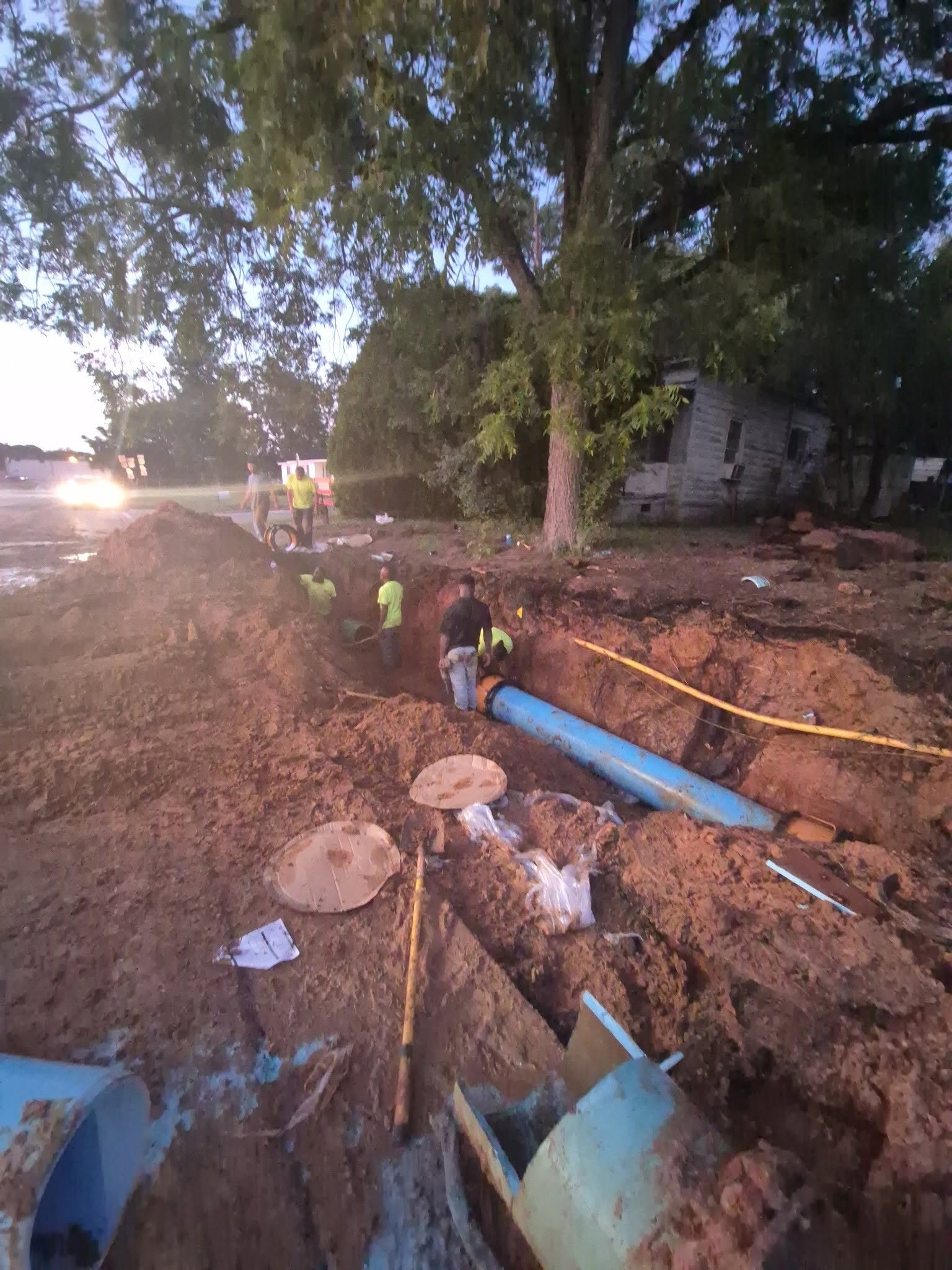 men working in the dirt with a big water pipe
